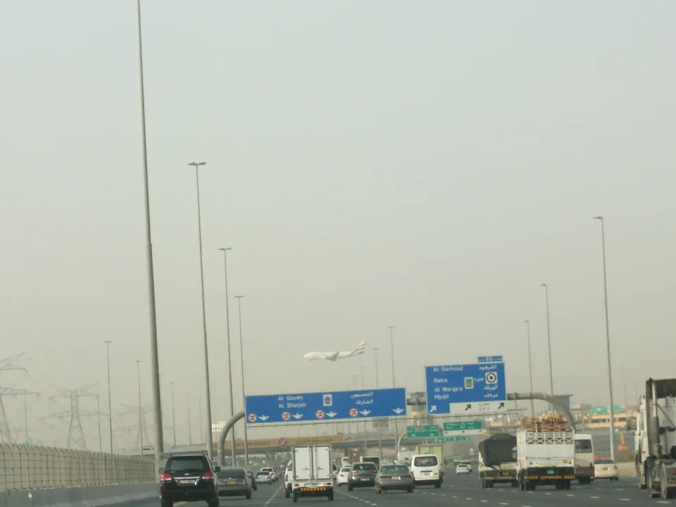 Traffic on Emirates Road in Dubai with a plane landing overhead